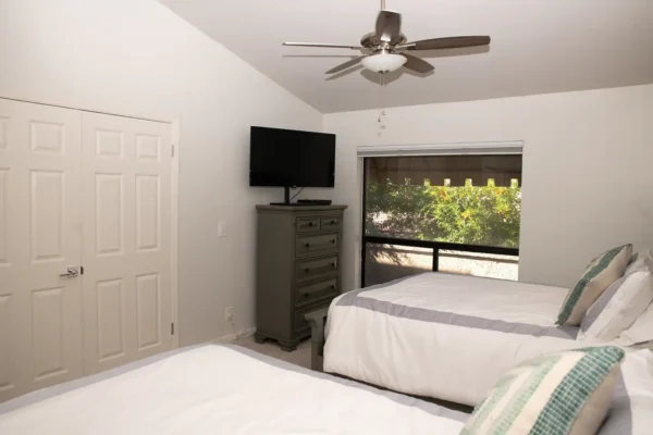 A bedroom with two beds and a flat screen tv.