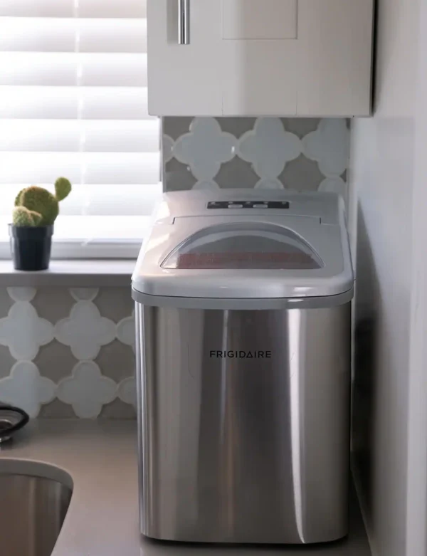 A stainless steel trash can in the corner of a room.