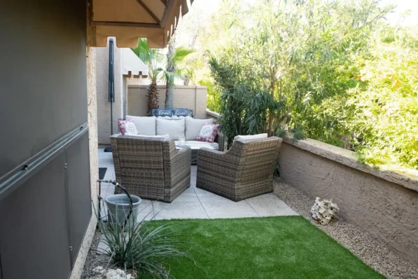 A patio with furniture and grass in the middle of it.