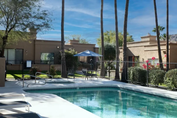 A pool with chairs and umbrellas in the background.