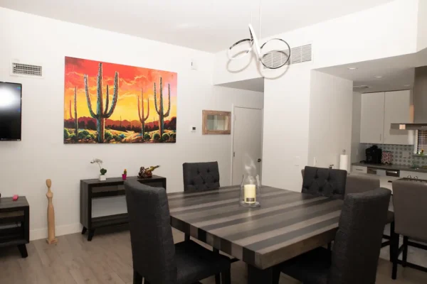 A dining room table with chairs and a painting on the wall.