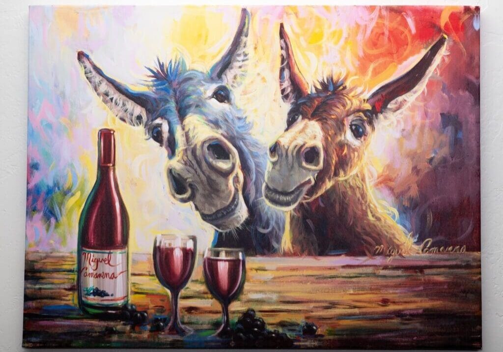 Two donkeys with wine glasses and a bottle